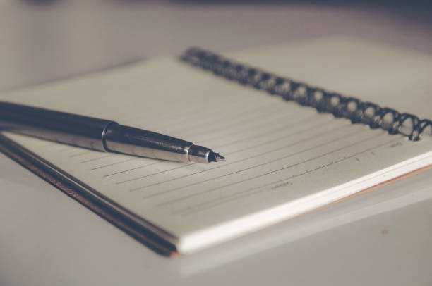istock closed up stainless steel Pen on blank notebook 886328786