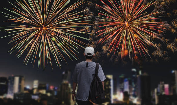 istock Young man with backpack looking firework in the city at night 886362474