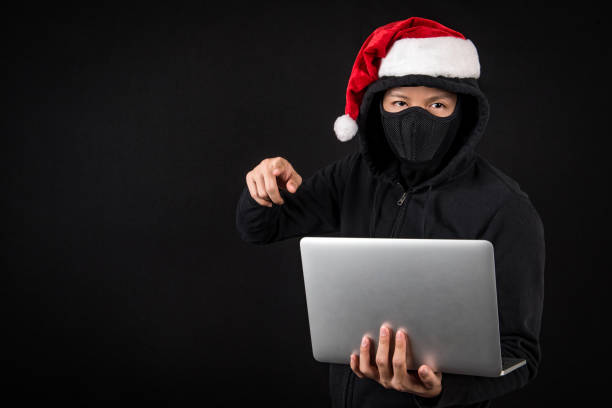 istock mysterious male santa hacker holding laptop computer 886378822