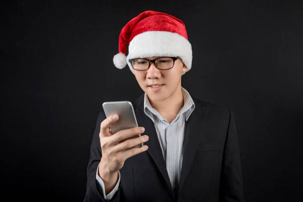 istock Young Asian businessman with santa hat using smartphone 886378938