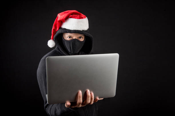 istock mysterious male santa hacker holding laptop computer 886378996
