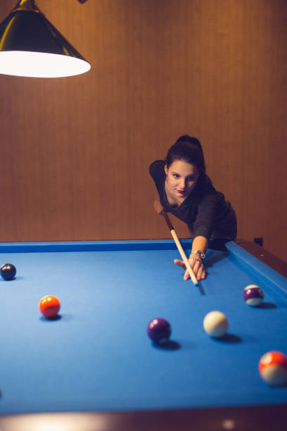 istock Young woman aiming at pool ball during billiard game. 886379138