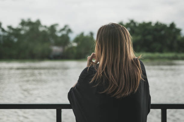 istock Lonely woman sitting and looking at the river 886379192