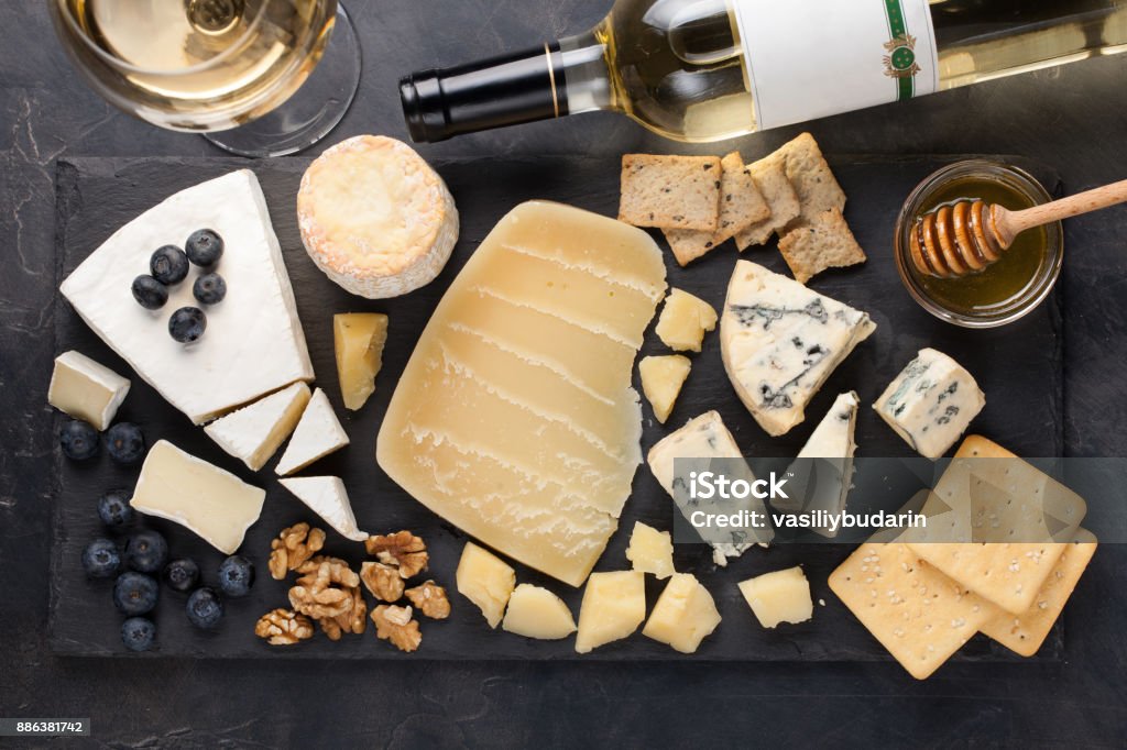 Tasting cheese dish on a dark stone plate. Food for wine and romantic date, cheese delicatessen on a black concrete background. Top view Tasting cheese dish on a dark stone plate. Food for wine and romantic date, cheese delicatessen on a black concrete background. Top view. Cheese Stock Photo