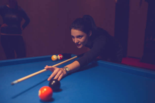 istock Young woman playing snooker in a pub. 886387578