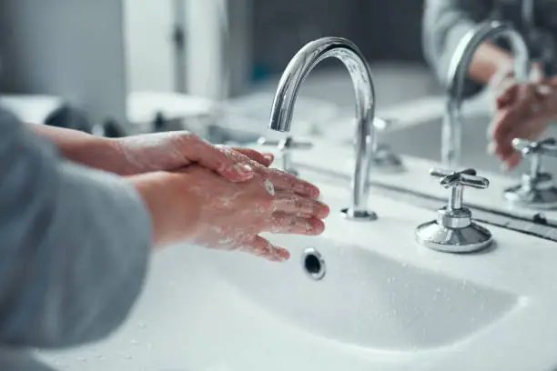Closeup shot of an unrecognizable woman washing her hands in the bathroom at home