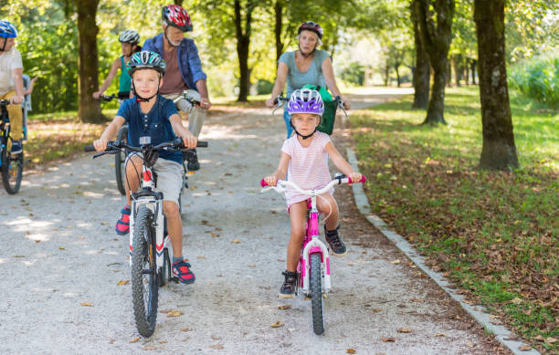 istock Family Cycling Together Through Park 886429384
