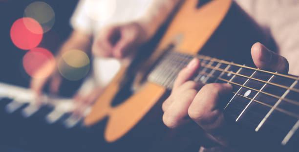 guy brouillage guitare acoustique avec fond joueur de piano - concert band photos et images de collection