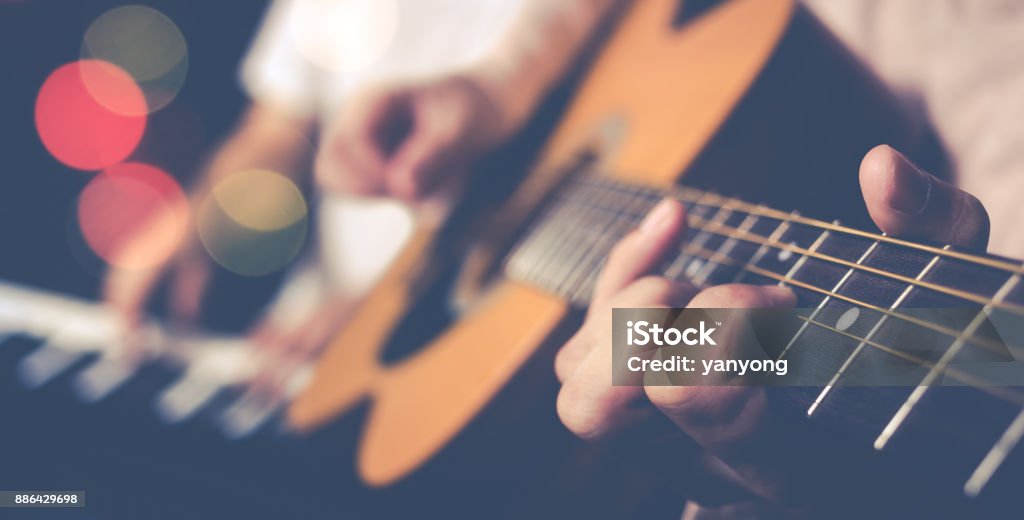 guy jamming acoustic guitar with piano player background Guitar Stock Photo