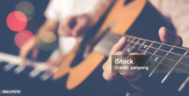 Guy Jamming Acoustic Guitar With Piano Player Background Stock Photo - Download Image Now