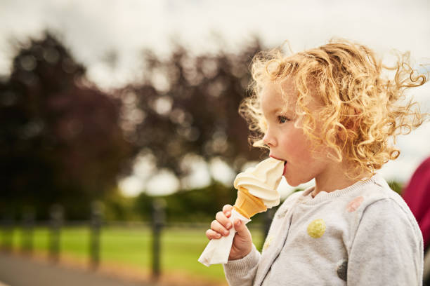 Fun and yum go well together Shot of an adorable little girl eating an ice cream cone outdoors licking ice cream cone stock pictures, royalty-free photos & images