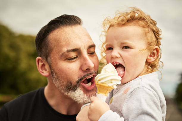 Ice cream is instant happiness Shot of a father and his little daughter eating an ice cream cone outdoors licking ice cream cone stock pictures, royalty-free photos & images