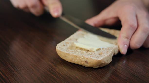 istock Female Hands Spreading Butter on Bread 886432544
