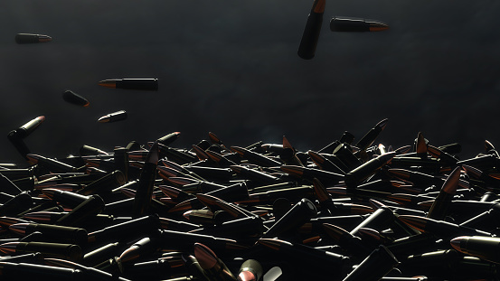 Many bullets fall on the table. In the background a dark wall.