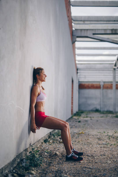 Happy athletic woman doing wall sit on a sports training.