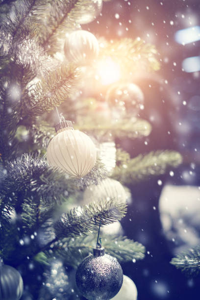 istock White and silver bauble hanging from a decorated Christmas tree with background. 886487972