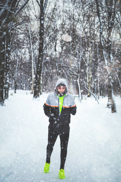 istock Man exercising / jumping and running in the park filled with snow. 886499516