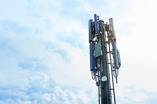 Low-angle look at a cellphone mast against a slightly cloudy sky. ample copy spacxe.