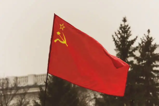 Old shabby red flag of the USSR on the flagstaff. The flag depicts a star and a sickle and a hammer. great October revolution