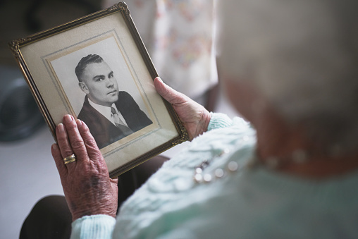 Cropped shot of a senior woman looking at an old black and white photo of a man