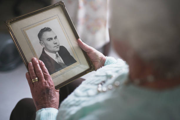 He was such a kind and caring man... Cropped shot of a senior woman looking at an old black and white photo of a man mourner photos stock pictures, royalty-free photos & images