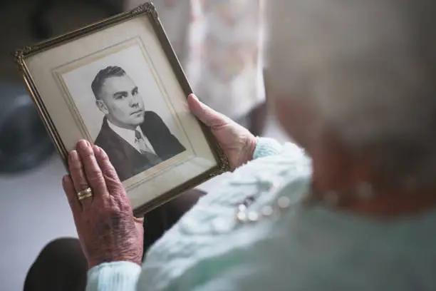 Cropped shot of a senior woman looking at an old black and white photo of a man