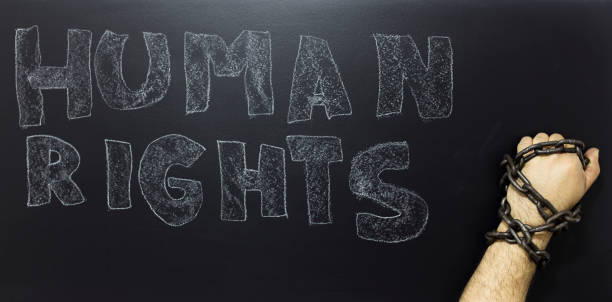 istock Human rights concept: chained man against the text: Human rights day written on blackboard. 886520324