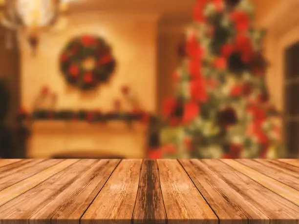 Photo of Wooden board empty table top on of blurred background. Perspective brown wood table over blur christmas tree and fireplace background, can be used mock up for montage products display or design layout