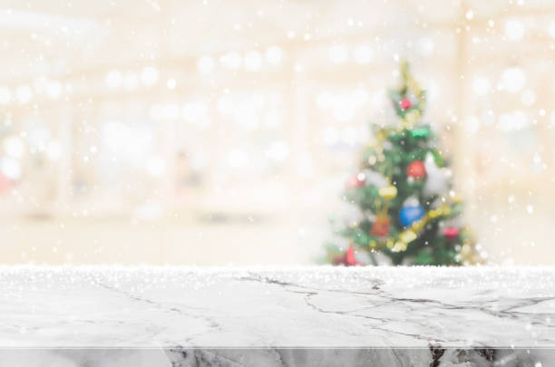 istock White marble stone table top on blur with bokeh christmas tree background with snowfall - can be used for display or montage your products 886530292