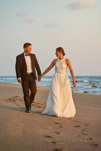 istock Happy groom and bride walk on beach 886530516