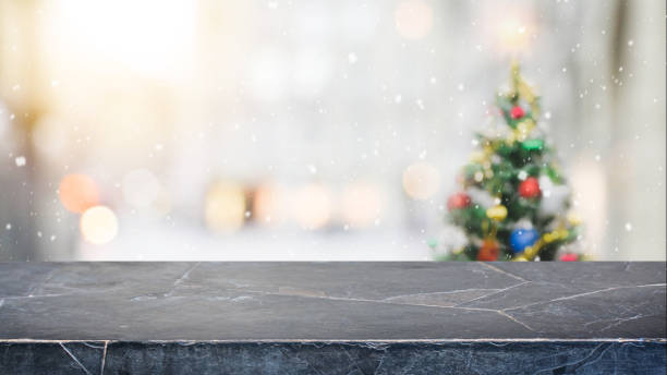 istock Black marble stone table top on blur with bokeh christmas tree background with snowfall - can be used for display or montage your products. 886533038
