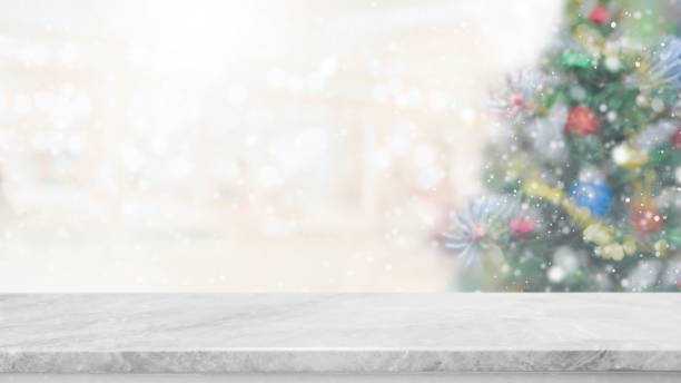 istock White marble stone table top on blur with bokeh christmas tree background with snowfall - can be used for display or montage your products. 886533098