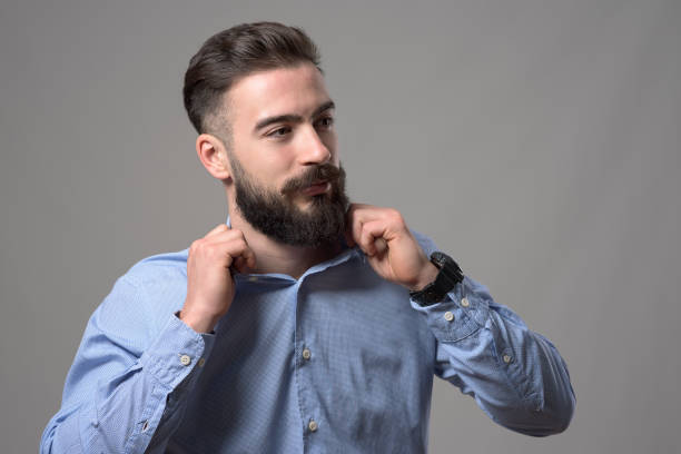 istock Young confident handsome bearded smart casual hipster adjusting shirt collar looking at copyspace 886533498