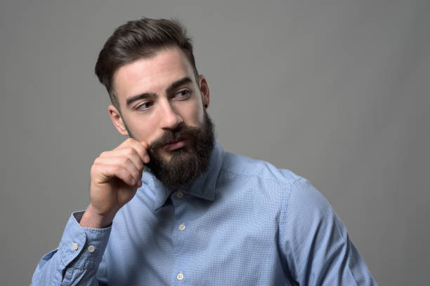 istock Young bearded smart casual hipster twirling mustache and looking back over the shoulder at copyspace 886538734