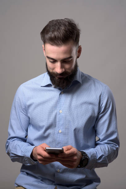 istock Young happy smiling bearded stylish business man typing message on mobile phone looking down at phone 886541734
