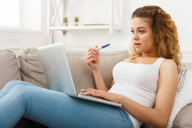 женщина просмотра на ноутбуке с тестом на беременность - pregnancy test test type medical test test method стоковые фото и изображения