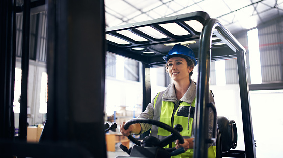 Cropped shot of an attractive young female stock controller driving a forklift through her warehouse
