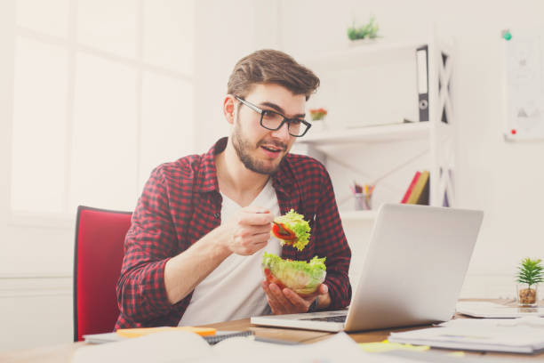 istock Man has healthy business lunch in modern office interior 886564664