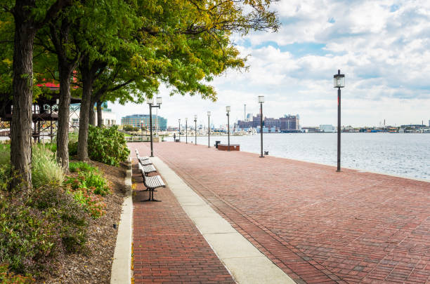 Waterfront Path on a Cloudy Autumn Day Watefront Path in Baltimore, Maryland, lined with Lamp Posts and wooden Benches. baltimore maryland stock pictures, royalty-free photos & images