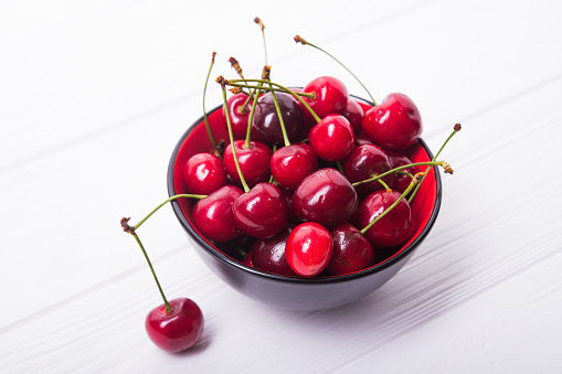 fresh red cherry fruit in plate on wood table