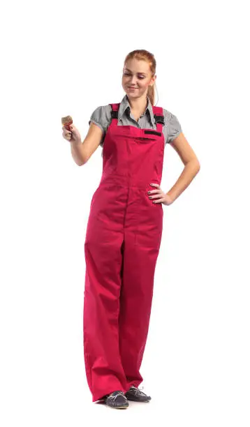 Young woman in red overalls with a paintbrush isolated on white background.