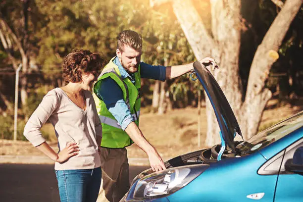 Shot of a young woman receiving roadside assistance from a young man after breaking down