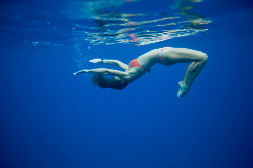 Woman in deep blue ocean swimming.