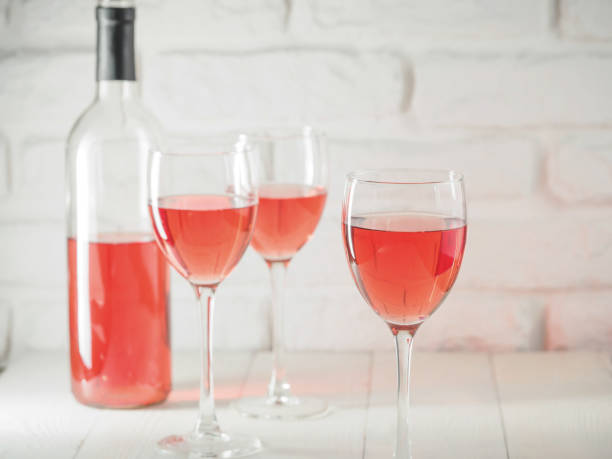 istock Three wineglass with pink wine and bottle on white brick wall background 886590860