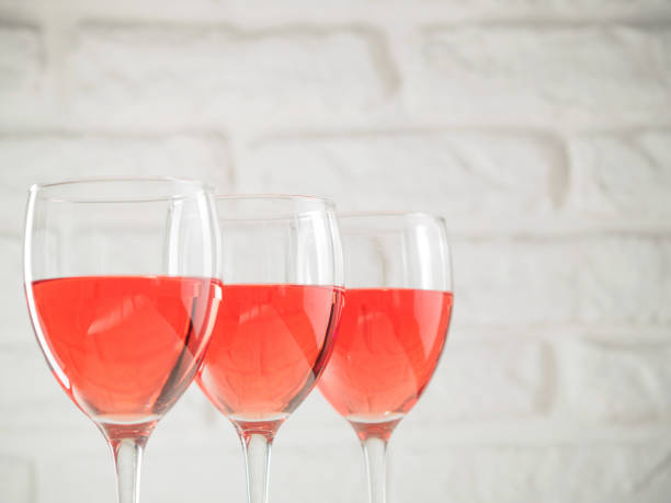 istock Three wineglass with pink wine on white brick wall background 886595002