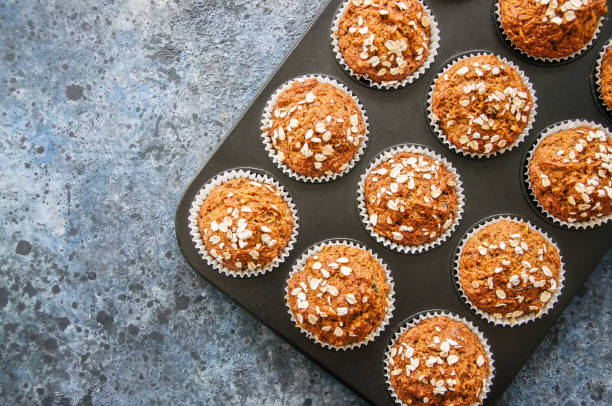 istock Carrot cake muffins with nuts, raisins and oats on a blue stone background. Top view with copy space. 886595356