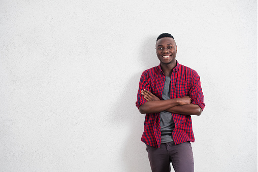 People and lifestyle concept. Portrait of happy and positive young African male in good mood, wearing red shirt smiling cheerfully showing his perfect white teeth
