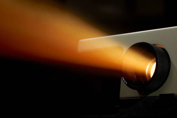 проектор световой луч ярко светит в темном фоне - кинопроектор стоковые фото и изображения