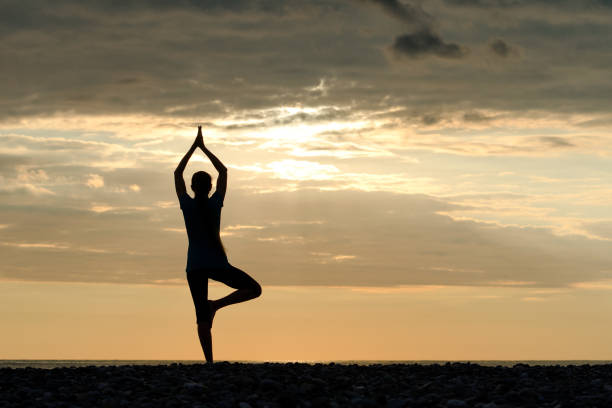 istock Girl at sunset practicing yoga at the seashore, silhouette 886620062