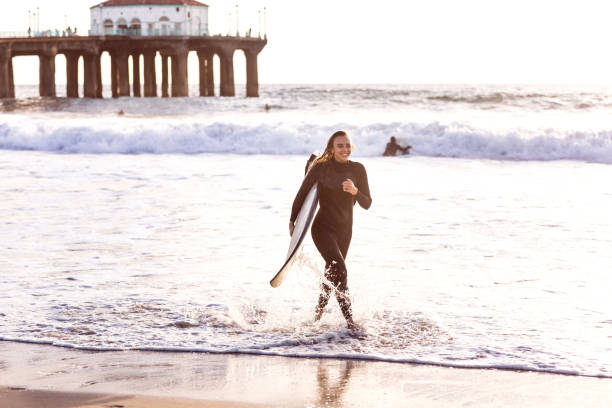 junge frau in kalifornien in großen wellen surfen gehen - santa monica surfing beach city of los angeles stock-fotos und bilder